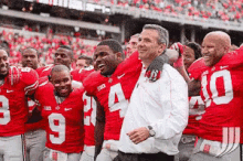 a group of football players are posing for a picture with a man wearing a white shirt with the number 10 on it