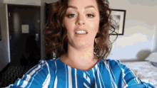 a woman in a blue and white striped shirt is making a face