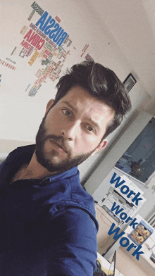 a man taking a selfie in front of a wall that says work work work on it