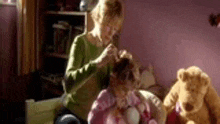 a woman is braiding a little girl 's hair in a room with teddy bears .