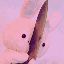 a stuffed bunny rabbit is holding a large knife in its mouth .