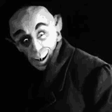 a black and white photo of a vampire wearing a mask and smiling .