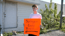 a young man is holding an orange sign pointing to the springdom county theater