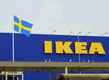 a blue and yellow flag flies in front of a large ikea sign