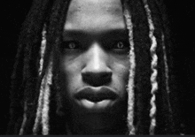 a close up of a person 's face with dreadlocks