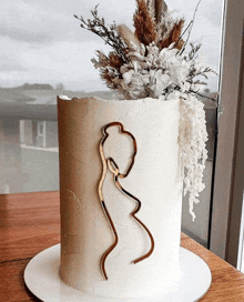 a white cake with a gold silhouette of a woman on it