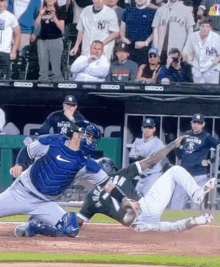 a baseball player is sliding into home plate during a game while a catcher watches .