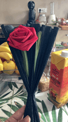 a bottle of zumo de melocuton sits next to a red rose