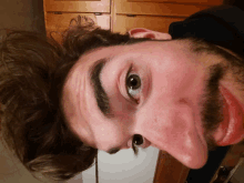 a close up of a man 's face with a wooden cabinet behind him