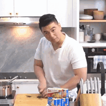 a man in a white shirt is preparing food in a kitchen with a box of his cheddar cheese in front of him