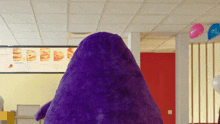 a purple stuffed animal in front of a menu