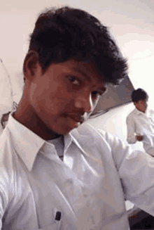 a young man in a white shirt and tie is taking a selfie with a pen in his pocket .