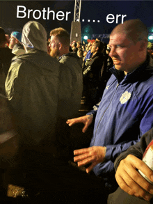 a man in a blue jacket stands in a crowd with the words brother ... err written on the top