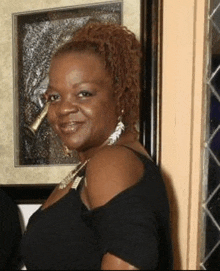 a woman in a black shirt is smiling in front of a picture frame