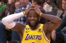 a man wearing a lakers jersey holds his head