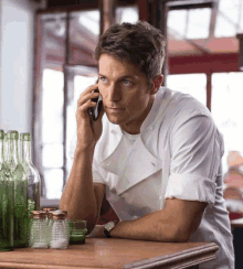 a man in a chef 's uniform is talking on a cellphone