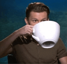 a man is drinking from a very large coffee cup .