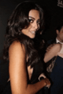 a woman with long dark hair is smiling in a black dress