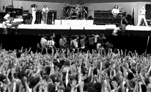 a group of people are standing in front of a stage with their hands in the air at a concert .