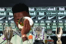 a man holding a soccer ball in front of several trophies including one that says abdullah somi