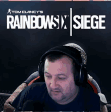 a man wearing headphones is sitting in front of a rainbow six siege poster