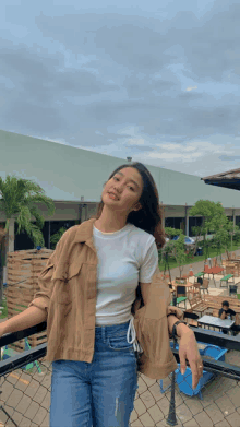 a woman standing on a balcony wearing a white shirt and jeans