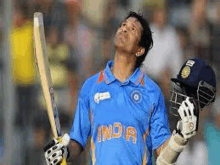 a cricket player is holding a bat and a helmet in his hand .