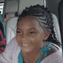 a little girl with braids and earrings is smiling