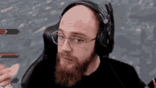 a bald man with a beard is wearing headphones and glasses while playing a video game .