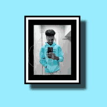 a man in a blue hoodie is taking a selfie in a mirror