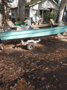 a boat with a trailer attached to it is parked in front of a house with a green lawn mower