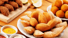 a variety of fried food on a table including a bowl of fried pastries