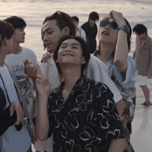 a group of people standing on a beach with one wearing a shirt that says ' s ' on it