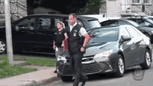 a man and a woman are walking down a street next to a car with the word police on it