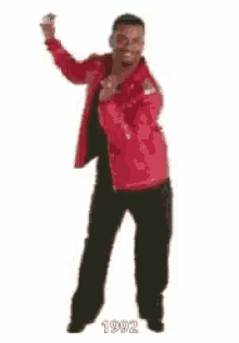 a man is dancing in a red jacket and black pants .