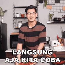 a man in a striped shirt is holding a plate of food with the words langsung aja kita coba above him