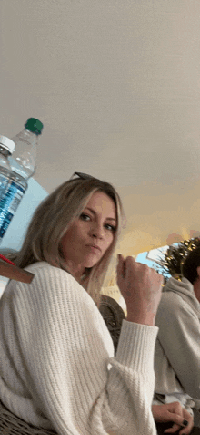 a woman sitting in front of a bottle of water