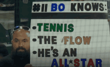 a man holding a sign that says # ii bo knows tennis the flow and he 's an all star