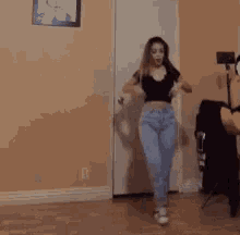 a woman is dancing in a room with a picture on the wall .