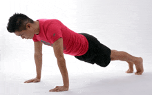 a man doing push ups with a red shirt that says reebok on it