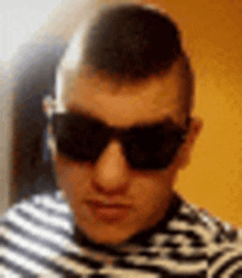 a man wearing sunglasses and a striped shirt is taking a picture of himself .