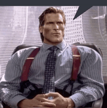 a man wearing suspenders and a tie sitting in a chair