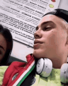 a man wearing headphones looks at the camera while a girl looks on