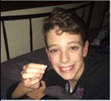 a young boy is laying on a bed holding something in his hand