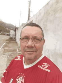 a man wearing a red topper jersey stands in front of a wall