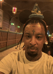 a man with a cross on his forehead wears a mickey mouse hat