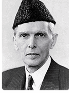 a black and white photo of a man wearing a suit and tie and a hat .