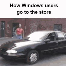 a man in a red shirt is standing next to a black car that says how windows users go to the store