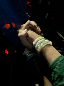 a person holding another person 's hand with bracelets on