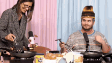 a man and a woman are cooking on a stove and the woman is holding a spatula with the word arc on it